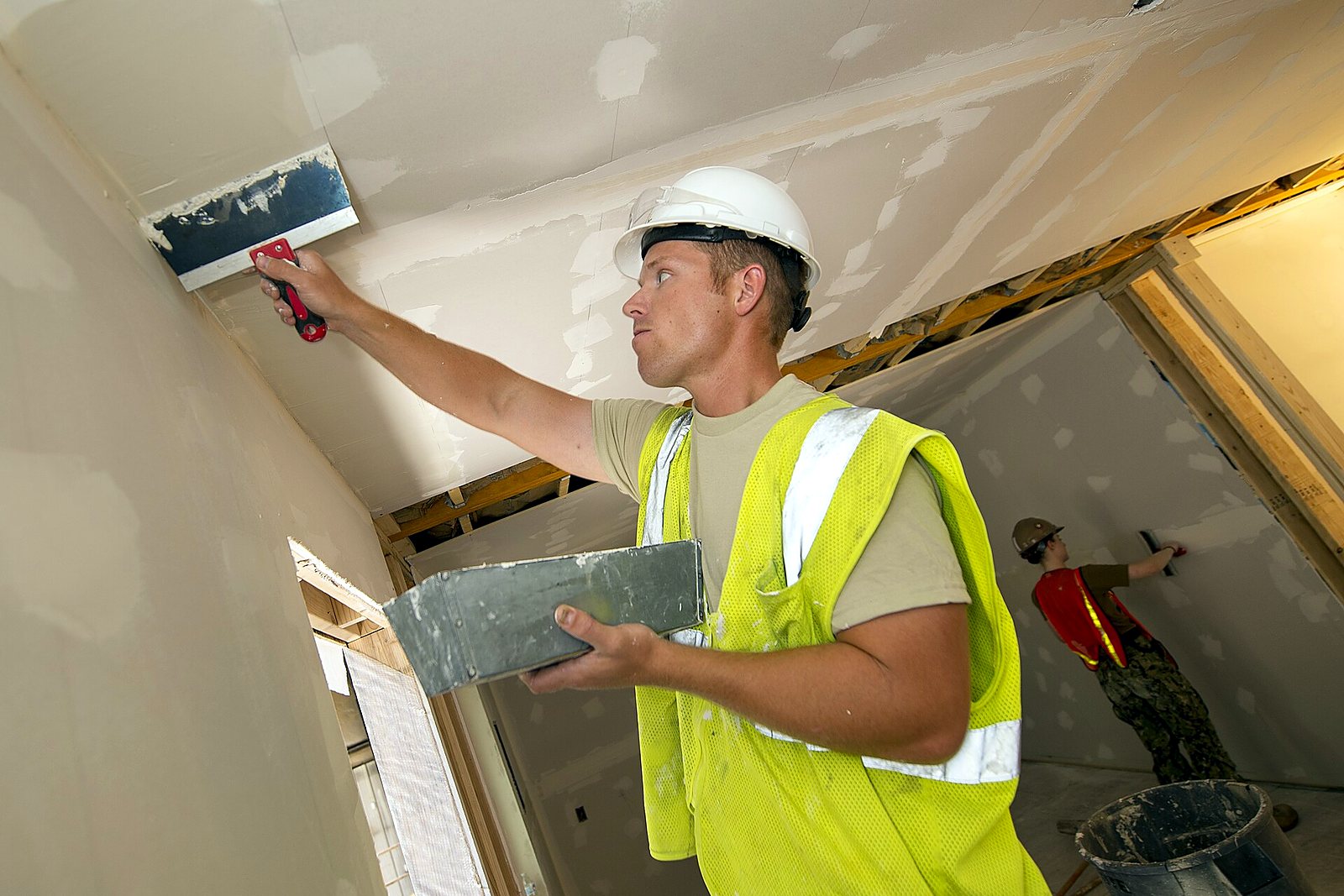 Finisher pressing tape into joint compound along a drywall seam